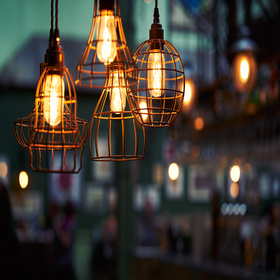 Old rustic lights hanging from the ceiling with a blurred background.