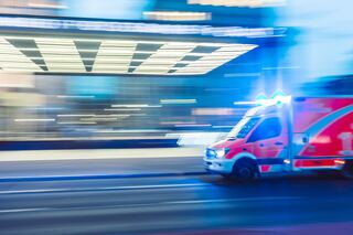 Motion blurred ambulance with lights rushing down a highway.