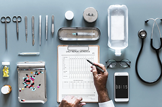 A table filled with various organized medical devices and equipment with a doctor's hand filling out a medical report.