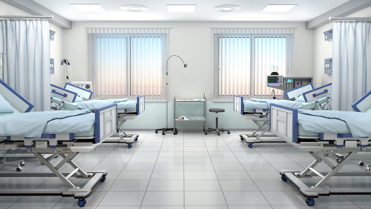 Hospital room with four hospital beds and other medical equipment.