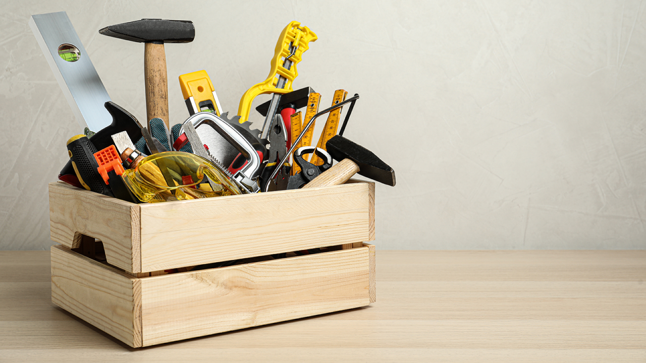 Crate full of different carpenter tools on a wooden table.